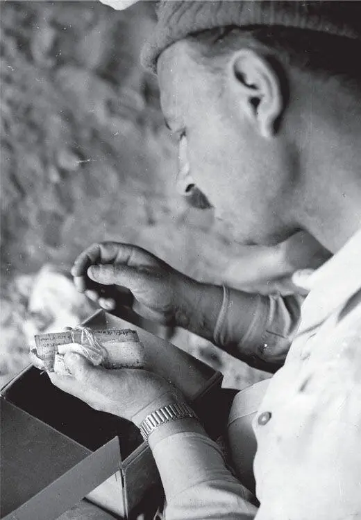 Archaeologist Yigael Yadin scrutinizing a piece of scroll on which Hebrew - фото 92