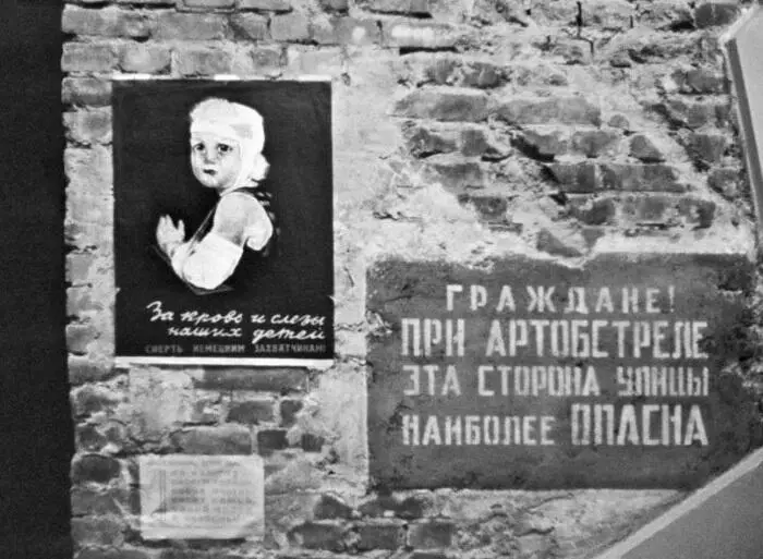 Предупреждающая жителей об обстреле табличка и плакат на стене жилого дома - фото 46
