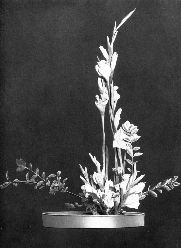Современная композиция икебана с гладиолусами и побегами вечнозеленых растений - фото 81